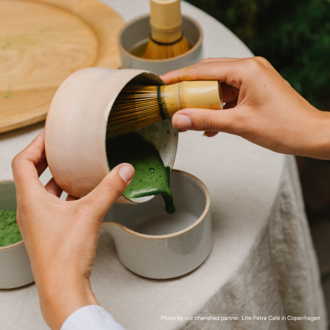 Matcha-Schneebesen in Glas mit Matcha-Tee, Outdoor-Szene bereitet grünen Matcha Tee zu