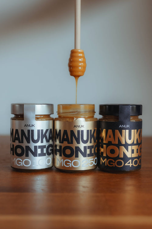 ANUK Manuka Honig im Glas, 100 MGO, Honiglöffel taucht in den Honig ein