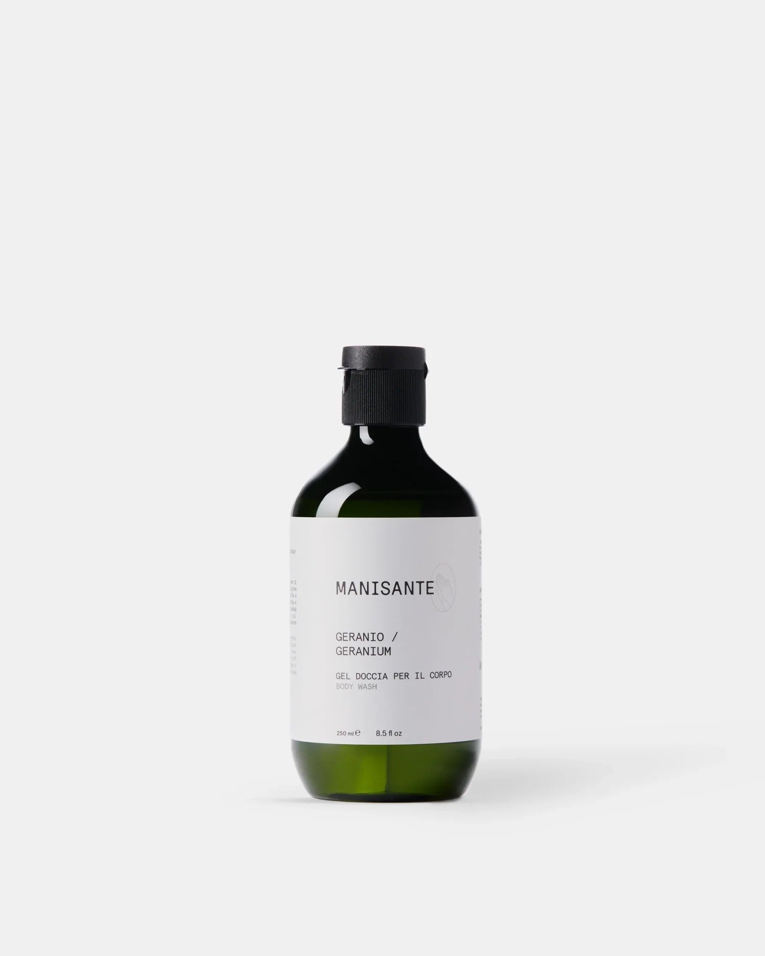 Manisante Duschgel Geranie in grüner Glasflasche vor hellem Hintergrund