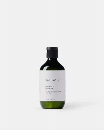 Manisante Duschgel Geranie in grüner Glasflasche vor hellem Hintergrund