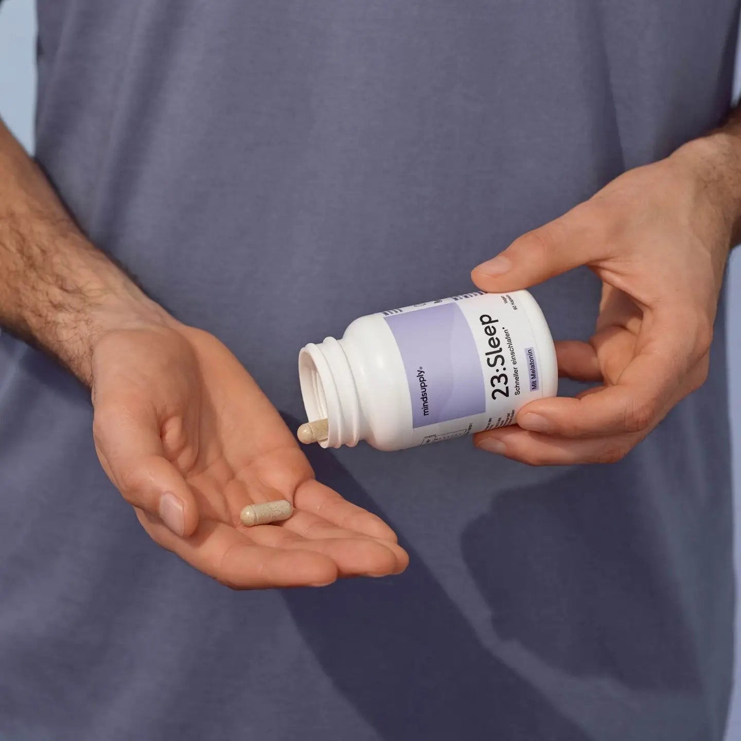 Veganes Sleep dose supplement wird aufgeschraubt und Kapseln sind in Hand vor lila Hintergrund zu sehen  