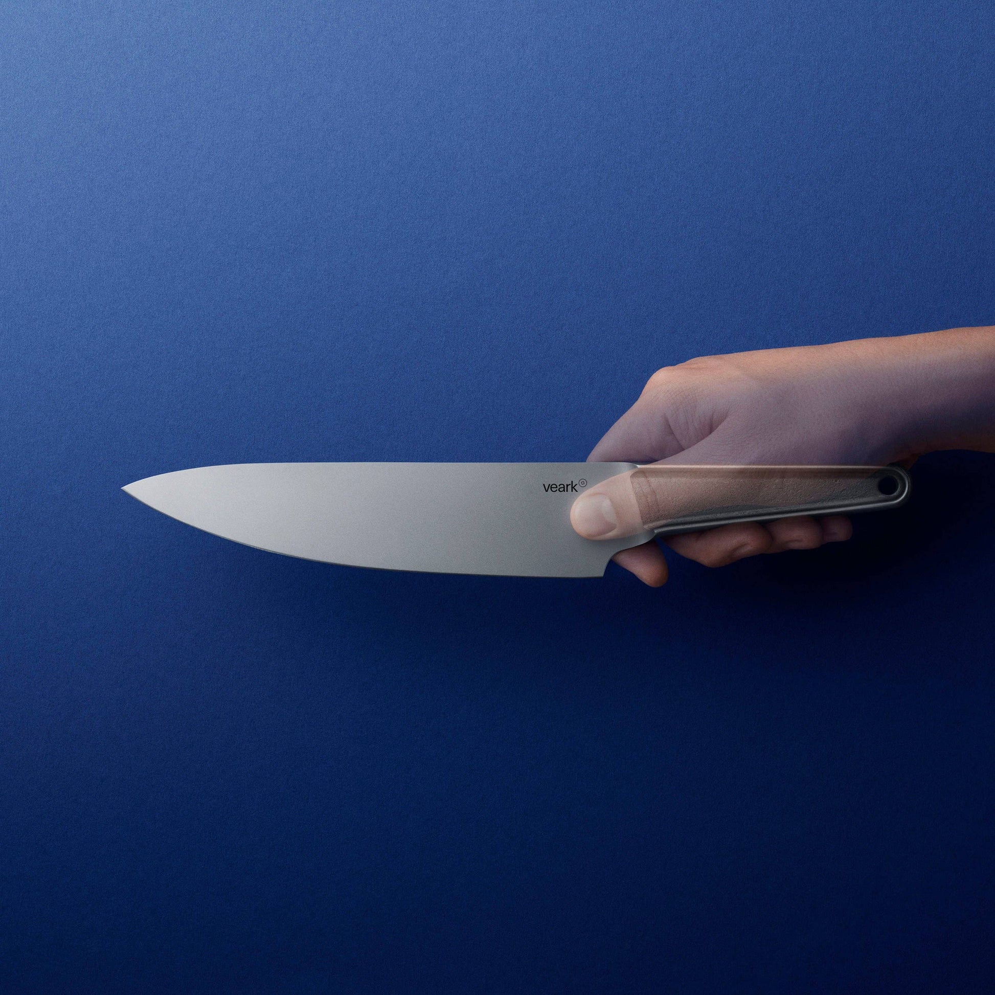 Kochmesser aus Edelstahl, frontal gehalten vor blauem Hintergrund, Handhabung zu sehen, Messer in halt halten 