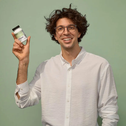 Focus supplement dose wird von Person vor grünem Hintergrund freudig hochgehalten 