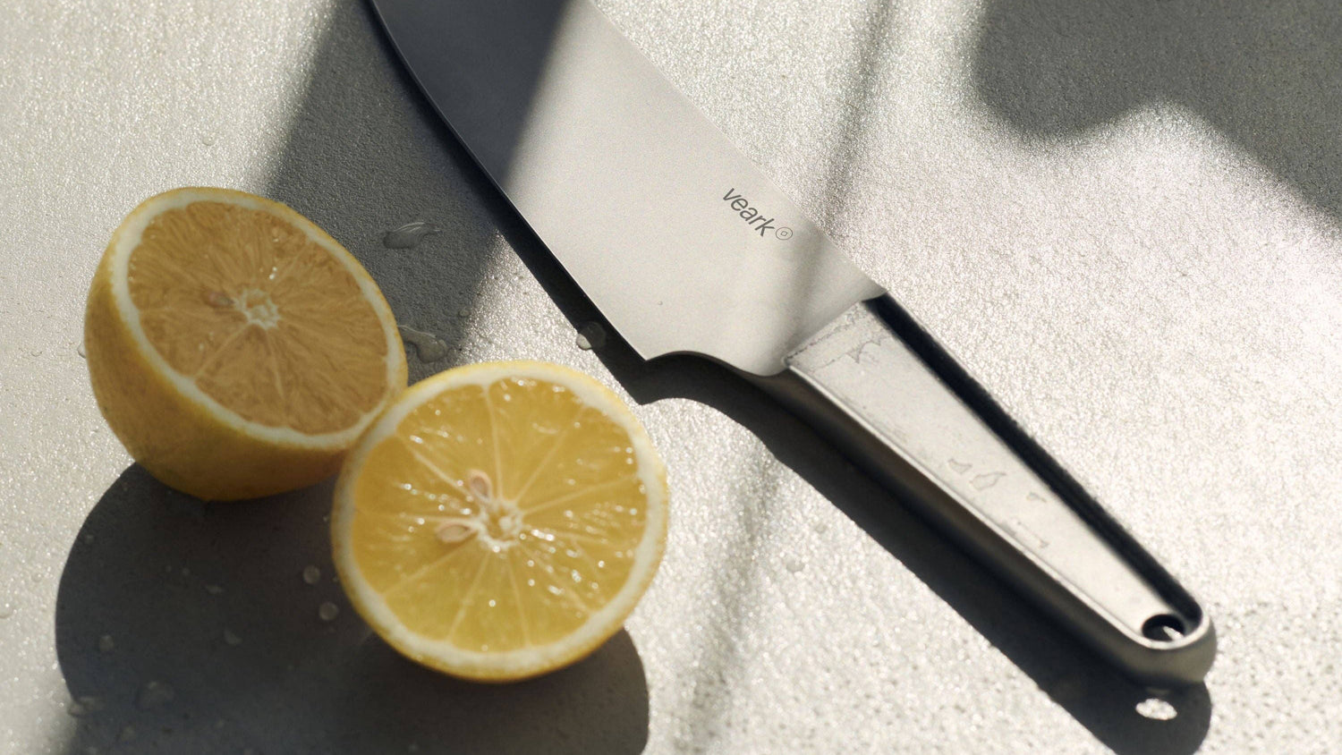 Edelstahl Kochmesser neben aufgeschnittener Zitrone auf Schneidebrett