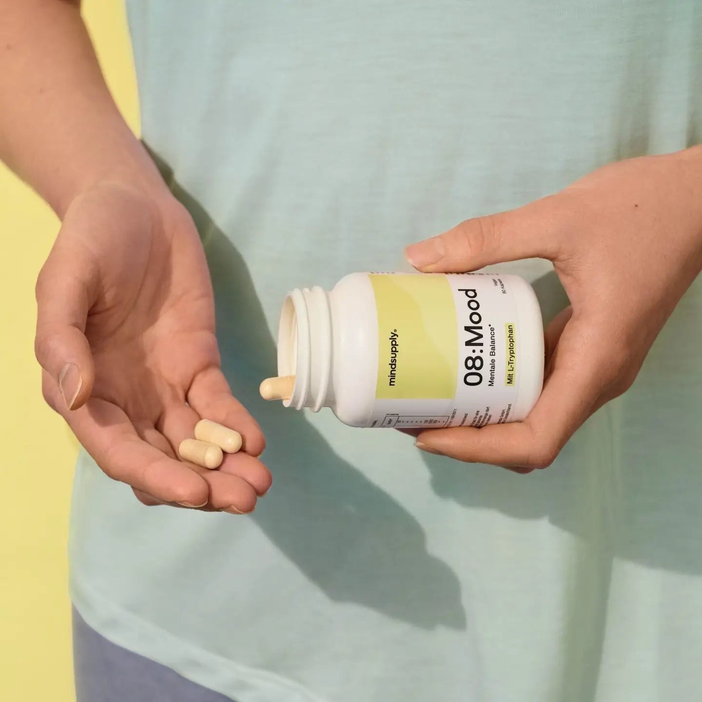Mood supplement dose wird in Hand geschüttet mit grün gelben Hintergrund