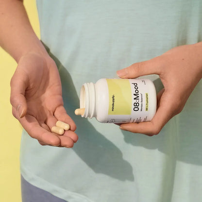 Mood supplement dose wird in Hand geschüttet mit grün gelben Hintergrund