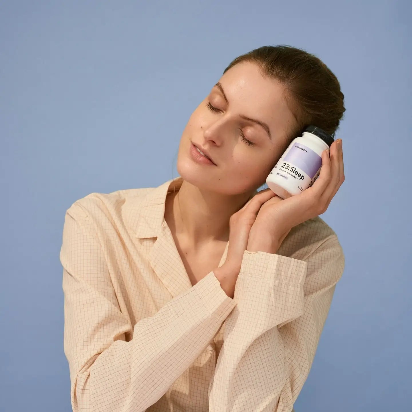 Sleep supplement wird von Frau hochgehalten vor blauen hintergrund