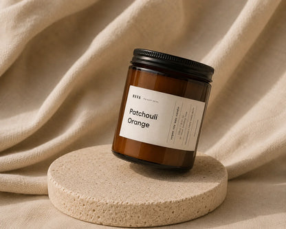 Sojakerze Patchouli Orange auf Steinpodest vor beigem Tuch